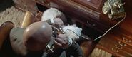 Blofeld answering a telephone at his desk, his cat sat on his lap.