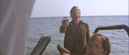 Claus holding a Luger P08 while struck in the back by a harpoon fired by one of Milos Columbo's men.