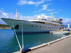 A large, sleek ship is moored at a quayside