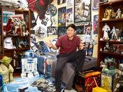 Leland Chee inmitten einer Menge Star Wars-Merchandise.