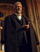 Cormac donned in a black suit with a blackish buttoned coat over his shoulders.