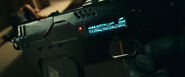 A closeup of the digital display on the side of Dredd's Lawgiver. The weapon appears to be set to semi-automatic ("SEMI") fire mode, shows an inactive integrated rangefinder (D for "Distance" with the readout at 0.0) and gives readings for the ammo loads for armor piercing ("AP"), incendiary ("IN"), high explosive ("HE") and standard full metal jacket ("FMJ")