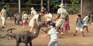 Kids petting the petting zoo's Apatosaurus, Gallimimus, & Triceratops.