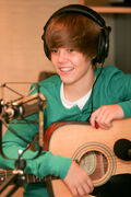 Justin Bieber smiling and holding his guitar