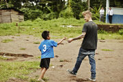 Justin Bieber giving pencil to kid