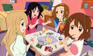 Mugi and the others eating snacks in Yui's room.