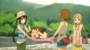 Yui jumps on the picnic blanket Ritsu and Azusa are trying to set up.