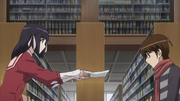 Shiori hands over a piece of paper to Keima