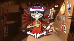 Noodle in her capsule hotel bunk while holding the MTV Moonman Trophy.