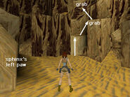 In the southwest corner of the cave, opposite the sphinx's left paw, is a light-colored block just the right height for climbing. Get on top of that block then take a standing jump to the angled block to the right. Turn around and take another standing jump to grab the brownish ledge above. Pull up.