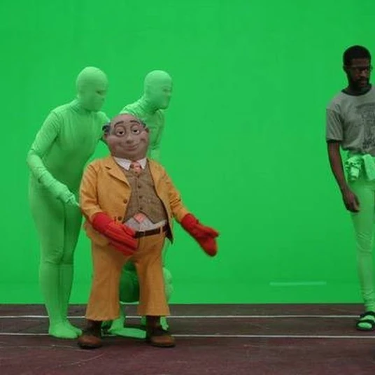 Prefeito Meanswell sendo manipulado por pessoas vestidas completamente de verde, este é o caso de programas que contém fantoches.