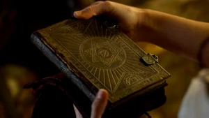 Kahlan holding the book inside Zedd's house.