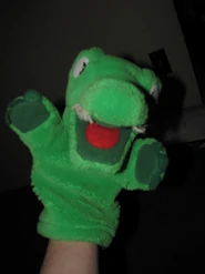 The alligator puppet on a hand.