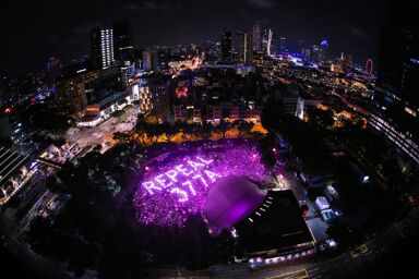 A photo taken from a nearby condominium from Hong Lim Park wherethe Pink Dot gathering and protest is held. The crowd is glowing with pink lights and across the crowd is spelt with bright pinkish white light, Repeal 377A.