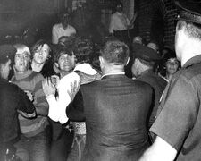 Black and white photograph of a crowd of people attempting to stop arrests at the Stonewall Inn.