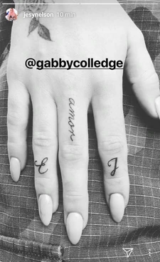 Jesy has the word "amor" and the letters E and J on her right fingers