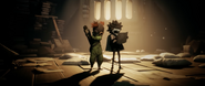 A Nome seen sitting on the left in the Little Nightmares III announcement trailer.