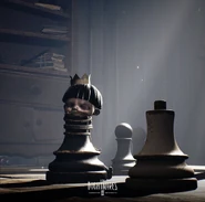 The deceased Bully tied to a giant chess piece with a crown on top of his head.