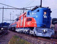 The GG1 in patriotic colors is hauling an Amtrak Passnger train with an Amtrak Electric locmotive.