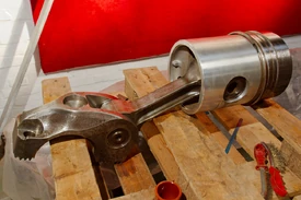 (Left to right) At the base of the connecting-rod there is an attachment (incomplete) called the 'big-end', that connects the whole assembly to the crank-shaft. The connecting-rod joins the 'big-end' to the piston (cylindrical object), of a diesel locomotive, via the gudgeon pin (clearly visible in the piston's side).Photo by Frédéric Bisson.