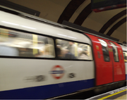 A 1995 Stock train speeds out of a station