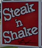 A typical Shake 'n Stake sign, which shows the wordmark on a red background being crooked a little bit. This location is in Elyria, Ohio.