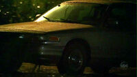  driving his government-issue Crown Victoria in the rain