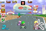 Luigi driving in between Toad and Wario in the original track, with Lakitu holding the Lap sign.