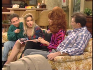 Kelly holding the TV Guide that they were waiting for in "Married... with Aliens".