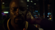 Amos' hand breaks against Luke Cage's cheek