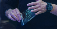 Tony Stark holding a J.A.R.V.I.S. mobile device while working with Bruce Banner.