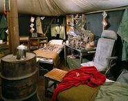 The Swamp replica exhibited at the Smithsonian from 1983-1985. Camera POV is at the dartboard. In the foreground is Hawkeye's cot with his red dressing gown. Image is from Smithsonian Archives, used with permission. Source details:.[6]