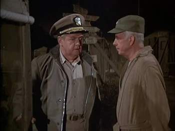 Cox with Potter entering the mess tent. The two stars on Cox's lapel can just be seen, indicating that he holds the rank of Rear Admiral.