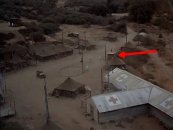 Airshot of the MASH compound from . The arrow shows the location of the latrine (the corrugated iron version). Just below it is the shower tent. The tent above it is the camp laundry.