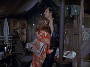 A view of the Swamp from "Edwina". In the background, Hawkeye's cot has been done up in special fabrics for the date. Note dart board (right) and airline seat (left) with still just visible. Dancing with the accident-prone Edwina, Hawkeye will shortly get himself burnt by the stove.