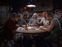 Poker game with Sergeant Cimoli. His helmet is in the foreground. The nurse in the distant background might be Nurse Shari, but cannot be sure.