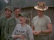 Margaret in a gray MASH sweatshirt. Here is one of the rare instances where she wears the M1951 field cap, more usually worn by the men. Scene from "End Run".