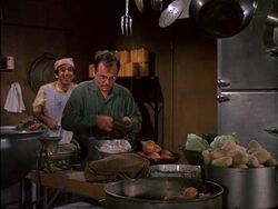 Radar in the kitchen with Klinger. It seems like there is no shortage of fresh vegetables in the camp, so why do they always complain about the food?