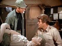 Father Mulcahy accompanies Captain Hill into battle to pick up a wounded soldier, posing as a "weight balance" for him, replacing the dummy "Little Mac" which Hill usually uses.