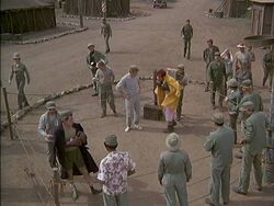 The MASH personnel gather to watch Zale and Klinger's fight. The ring has been set up in the area around the basketball hoop.