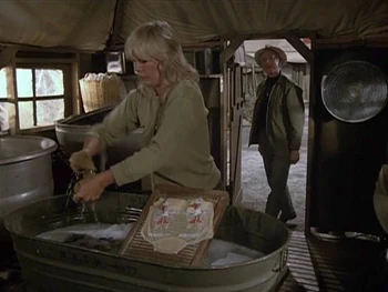 Margaret doing her personal laundry in one of the wash basins. Another one is hanging on the wall. Scene from .
