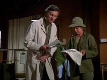 Hawkeye looks in on patient Private Webster in post-op. With him is Nurse Jo Ann in one of her many uncredited appearances.