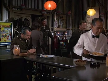 A view of the interior furnishings early in the series, from  (Season 1). There are Japanese prints or paintings on the walls. Two slot machines are to the right and on the left is a pinball machine. The piano will be there in later seasons.