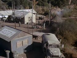 A rare view of the camp from this angle. Potter is entering the camp from between his tent and the hospital building. The stage is center, O Club is lower left. To the right, beyond the bushes should be the minefield.