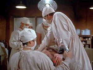 The anesthetist is probably Leland. Hawkeye just called for "Leland" to put the patient under in a scene from "Bombed".