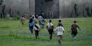 Carl running with Thomas, Teresa, Newt, Minho, Gally, Frypan, Winston, Zart, Billy, Mike and three unnamed Gladers to the doors.