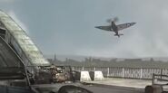 A spitfire flying over the bridge.
