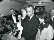 Johnson taking the oath of office aboard Air Force One, Jacqueline Kennedy to his left