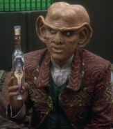 Quark holds an empty bottle of Aldebaran whiskey