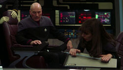 Picard operates the armrest intercom while Troi grips her console handrail in 2379